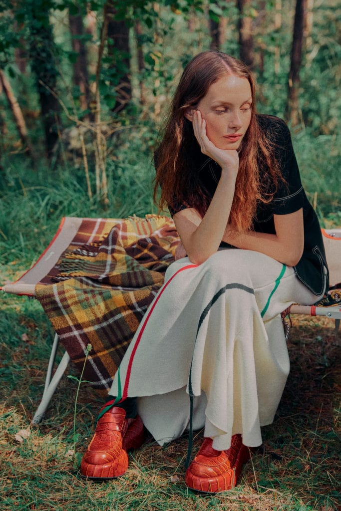 Clara가 COURRÈGES의 셔츠와 LOEWE의 치마와 신발을 착용하고 있다.