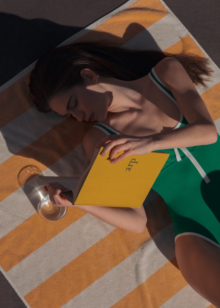 Anna wears a swimsuit by ERES and lies on a towel by HAY.
