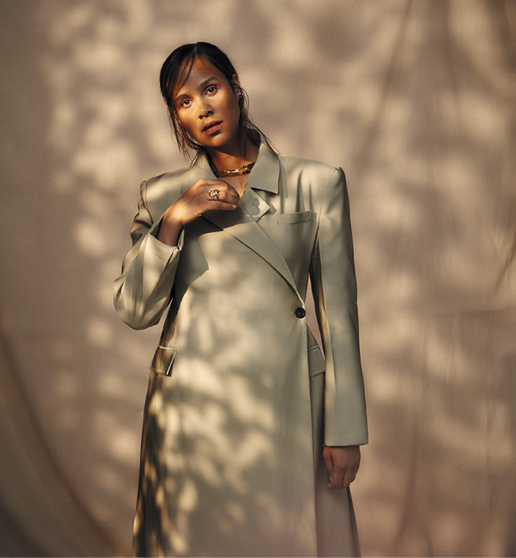 애슈턴이 입은 코트 by Peter Do, 목걸이 by Jil Sander, 이어커프 by Charlotte Chesnais, 귀걸이 by Jennifer Fisher.